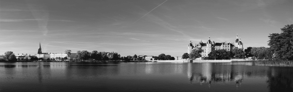 Une photo en noir et blanc d'un lac avec un château en arrière-plan.