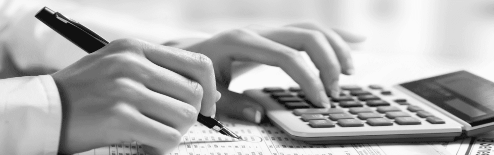 Une personne utilise une calculatrice et écrit sur un morceau de papier.