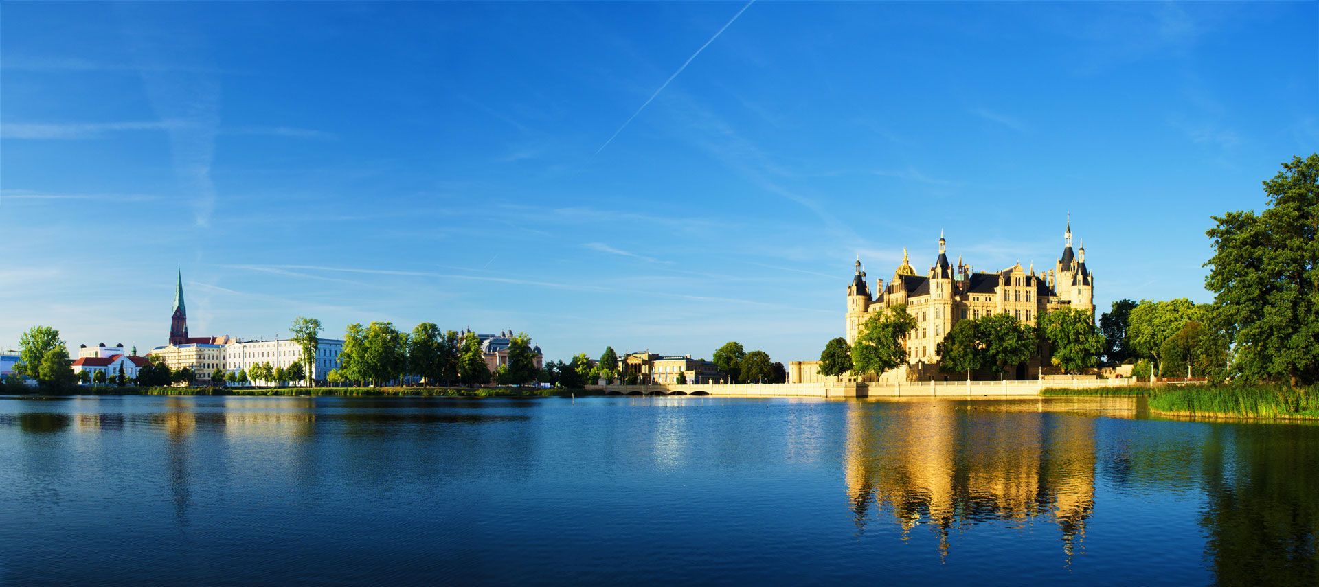 Un grand château se reflète dans l'eau d'un lac.
