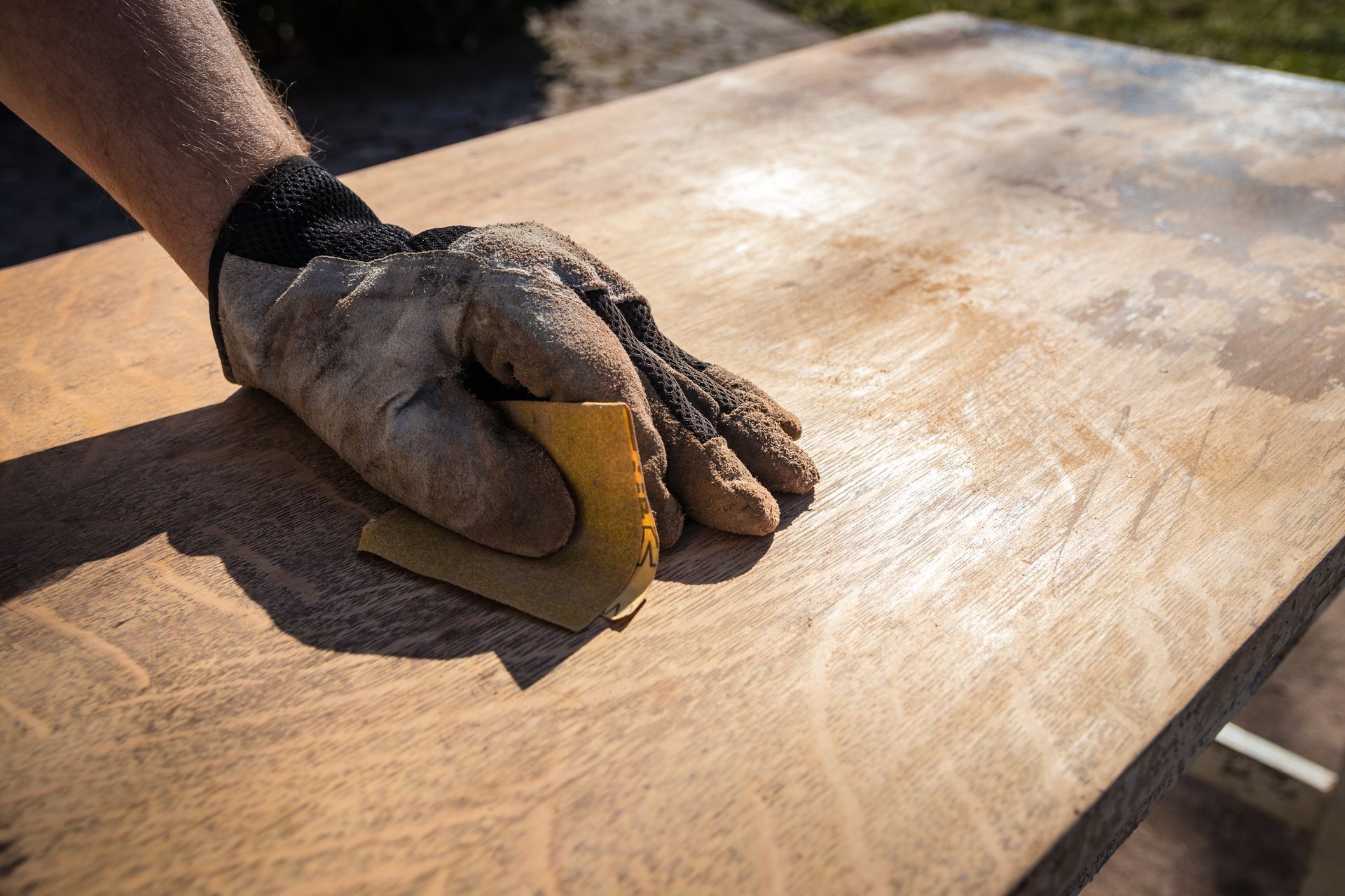 An individual sanding furniture to prepare it for refinishing.