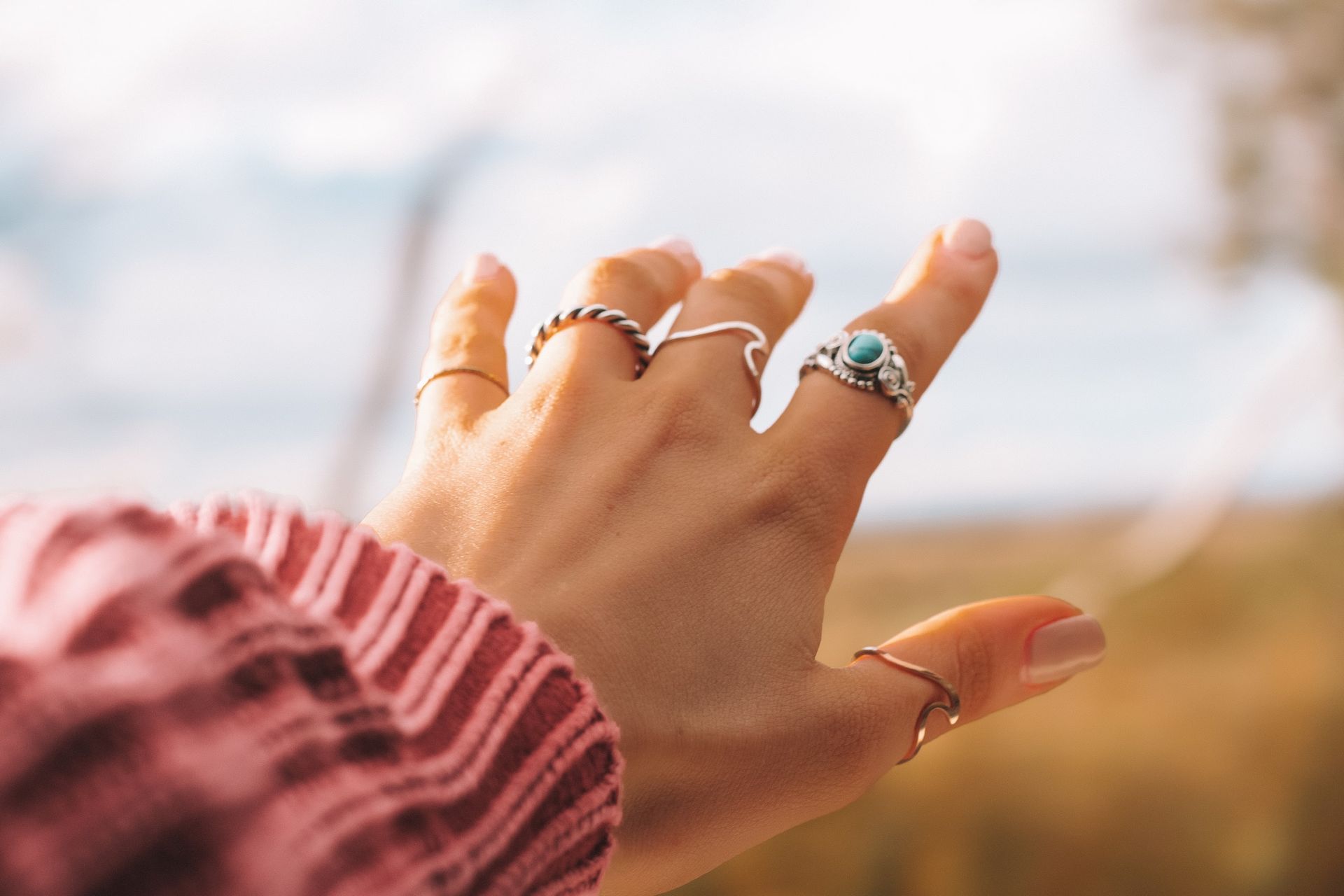 A close up of a woman 's hand with many rings on it.