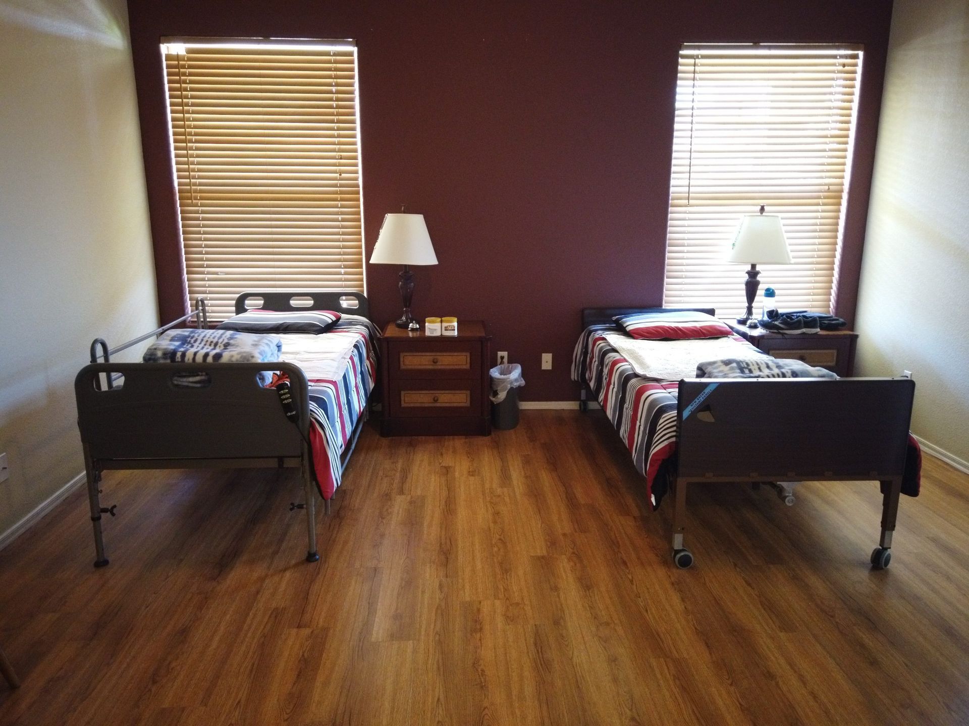 A bedroom with two beds and two windows with blinds