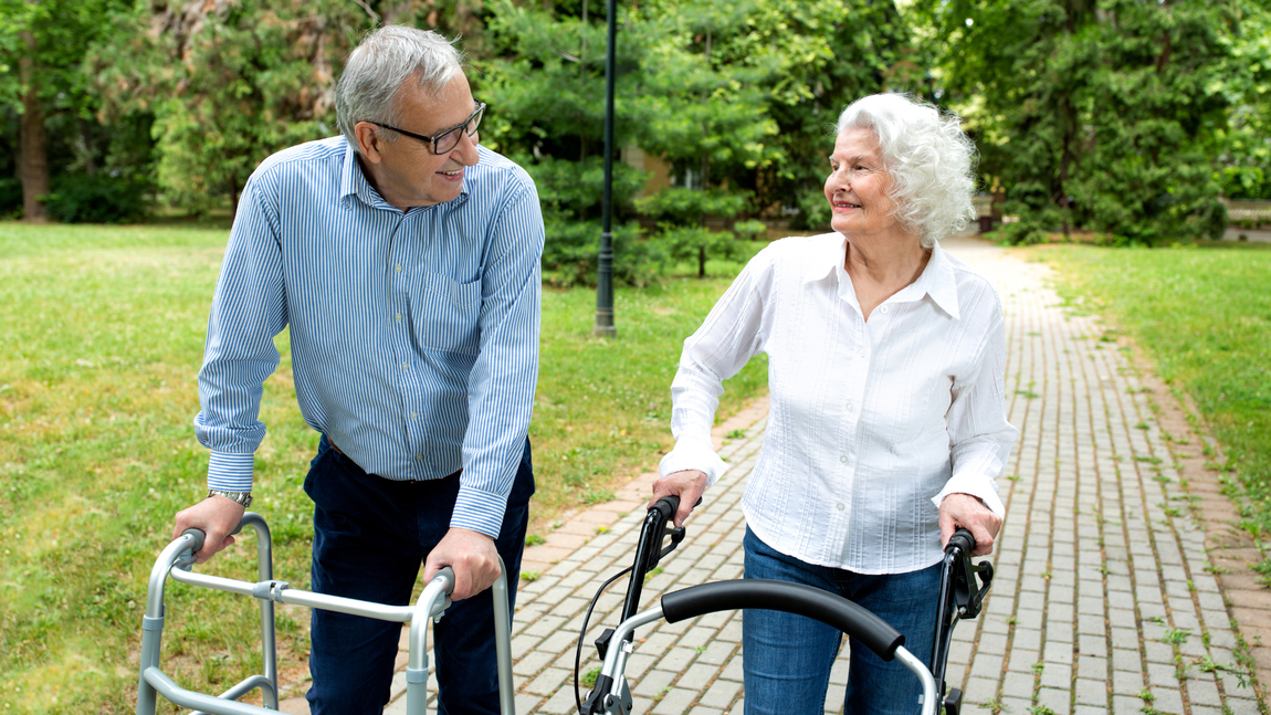 A man is helping an elderly woman with a walker.