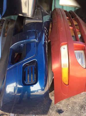 Blue and red car bumpers stacked together, showing front details and side lights.