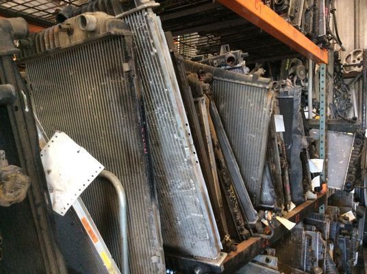 Pile of used radiators in a warehouse, many stacked vertically.