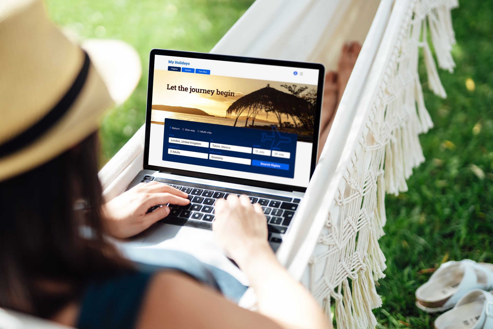 Woman using laptop while relaxing in a hammock outdoors, possibly booking a trip.