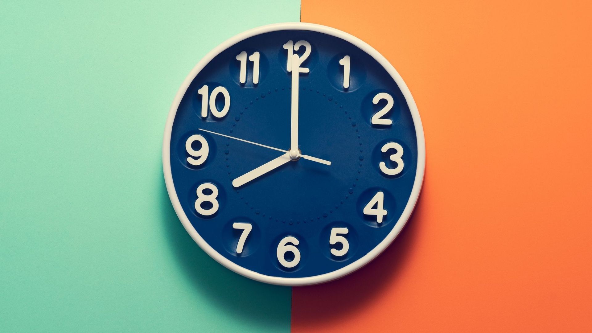 Clock showing the time is 8:00 on a two-toned background; teal and orange.