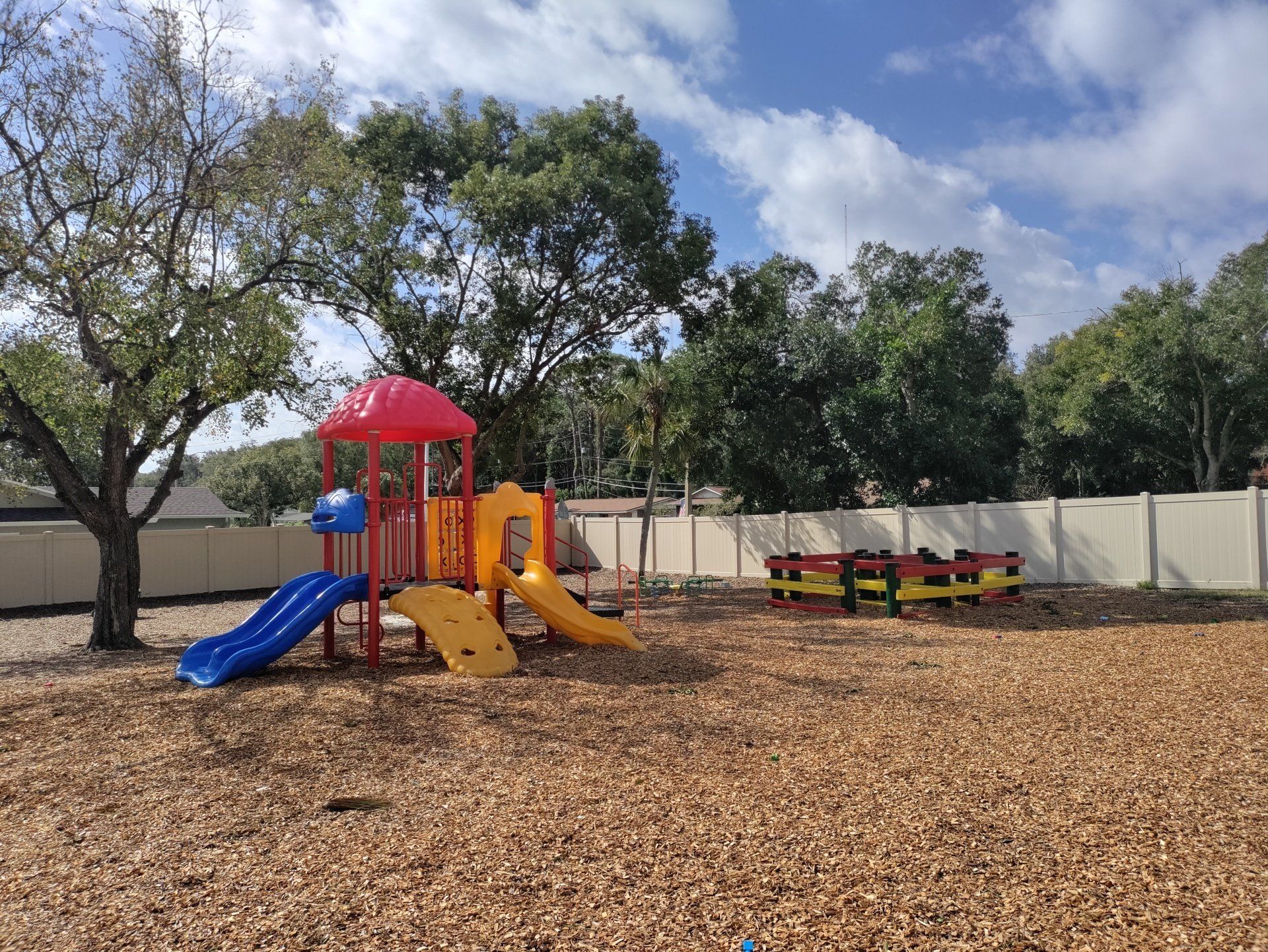 A colorful playground with a slide and a tree in the background.