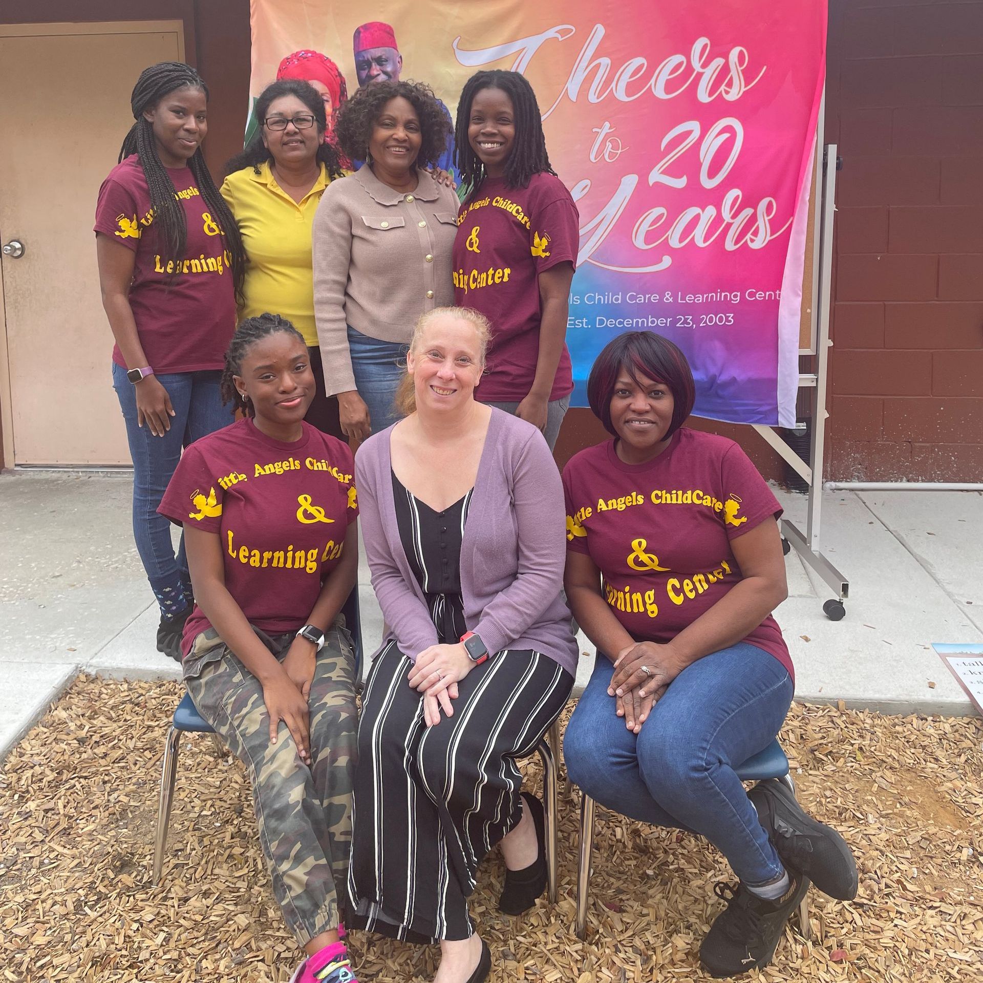 A group of women posing in front of a sign that says cheers to 20 years