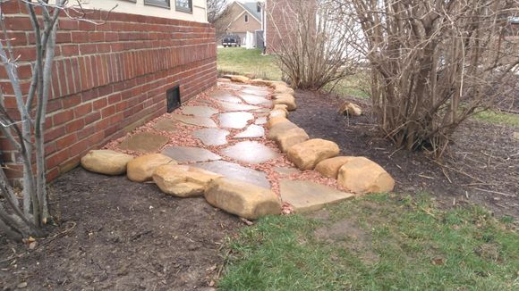 A stone walkway is leading to a brick building.