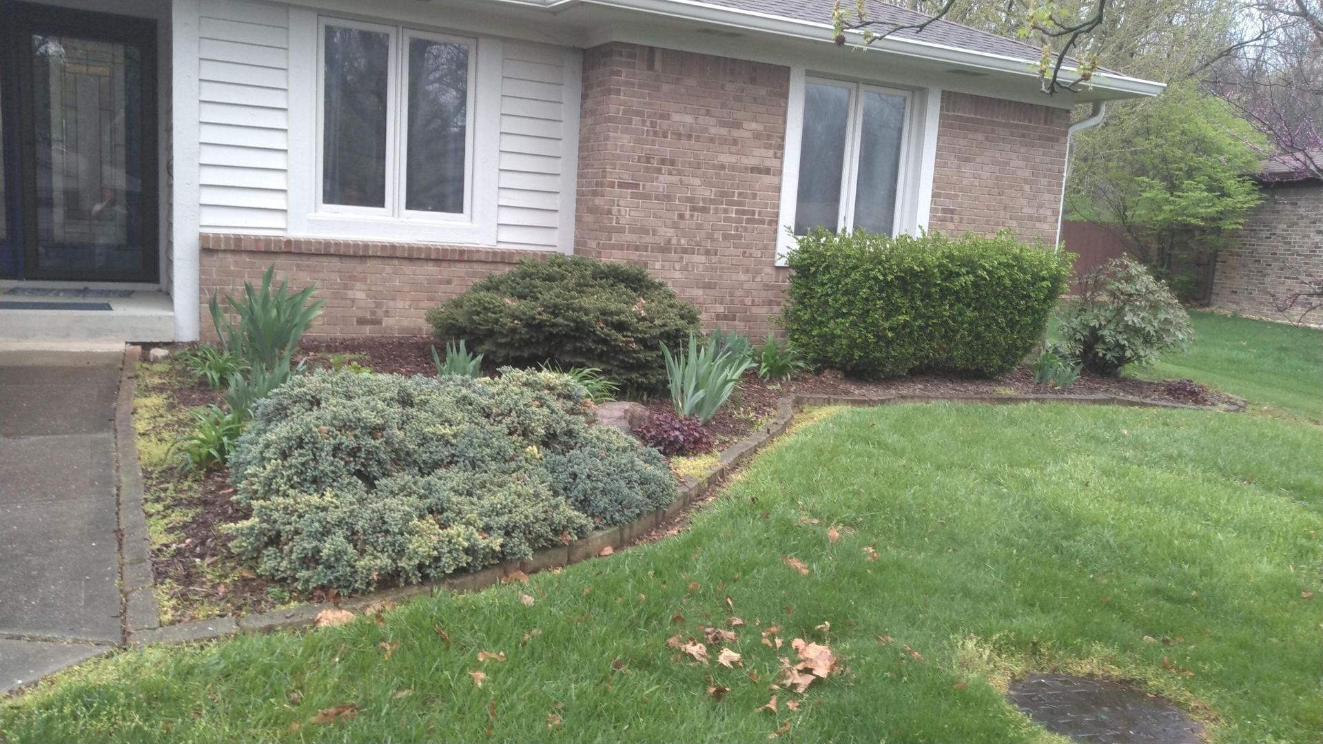 A brick house with a lush green lawn in front of it
