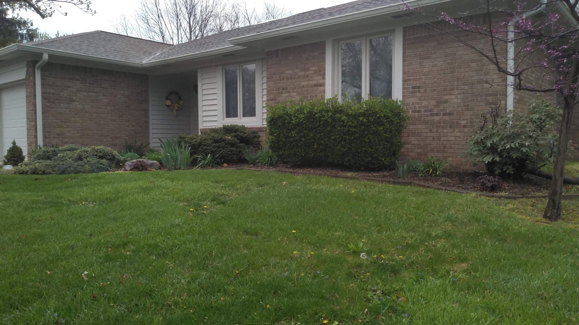 A brick house with a large lawn in front of it.