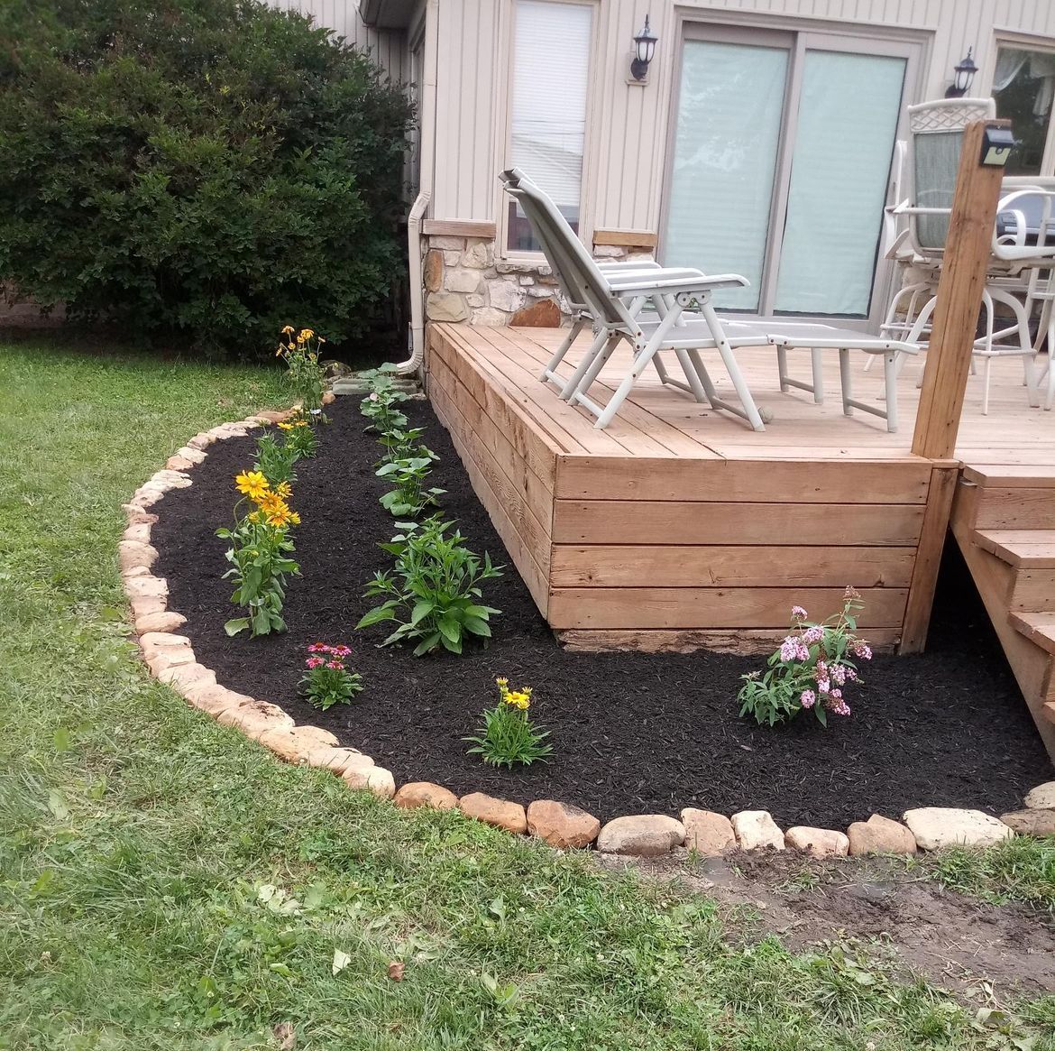 A wooden deck with chairs and flowers in front of a house