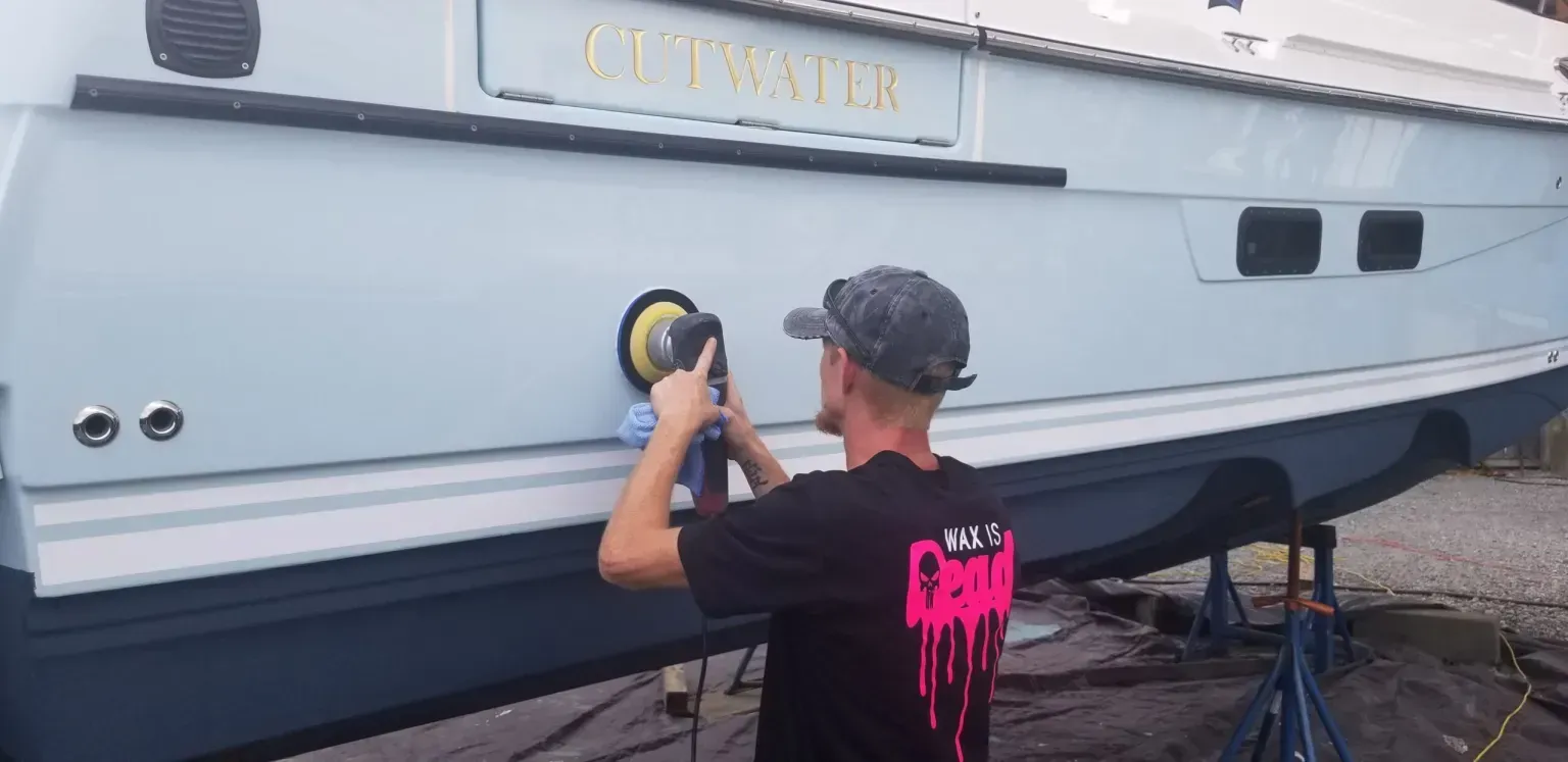 A man is polishing the side of a boat.