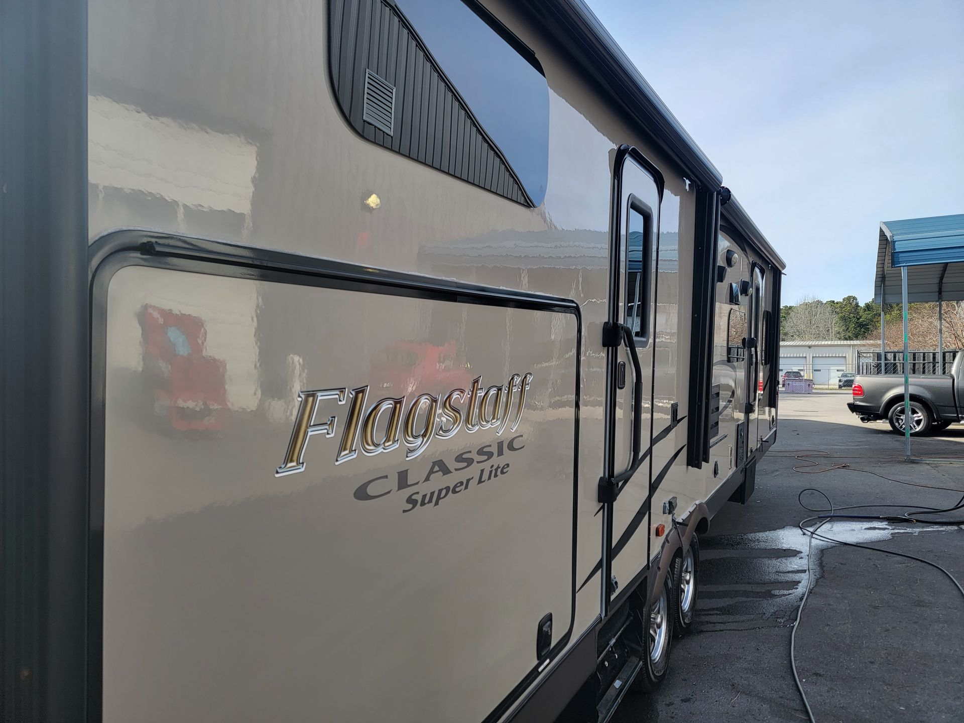 A rv is parked in a parking lot with a truck in the background.