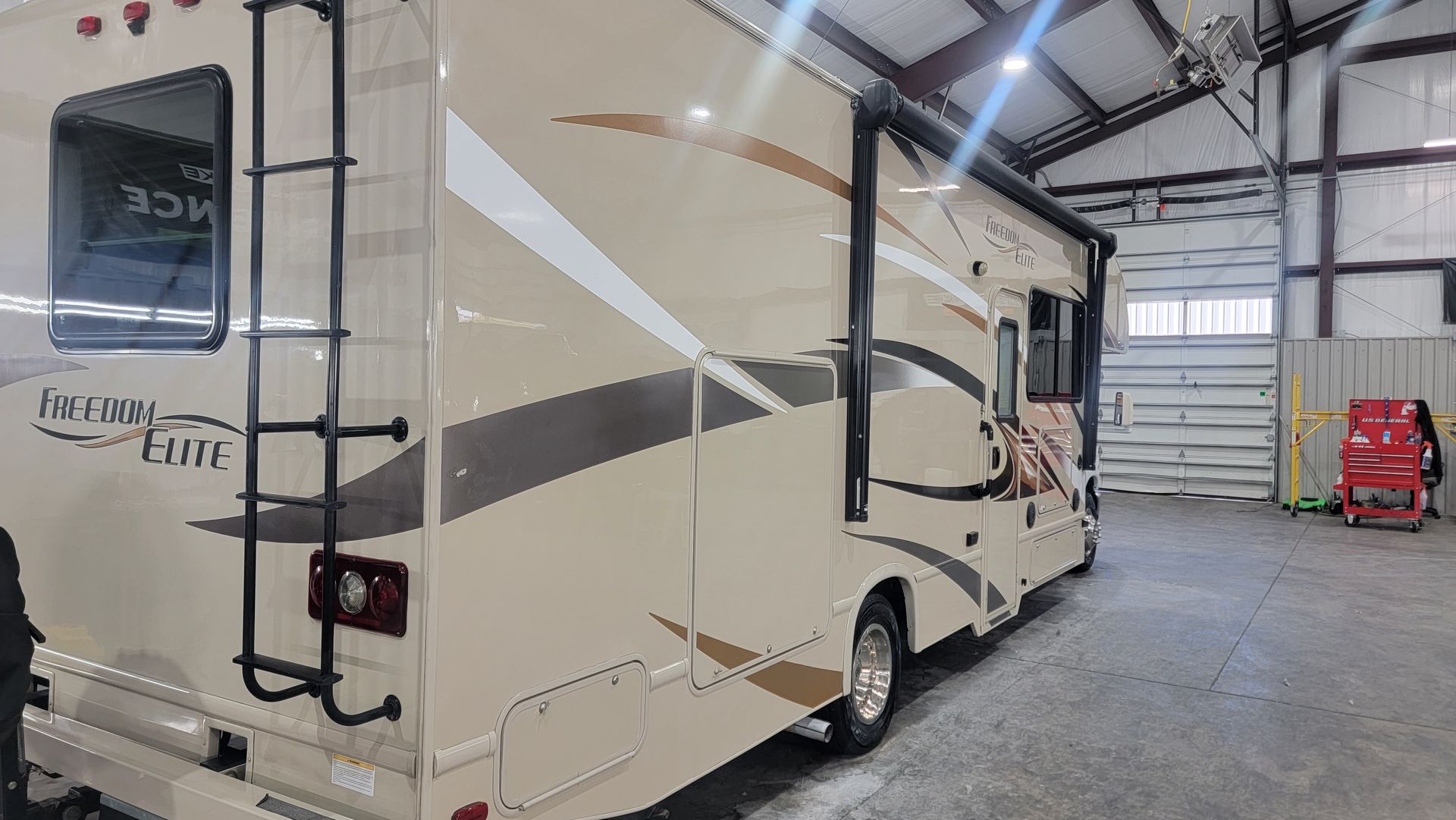 A large white rv is parked in a garage.