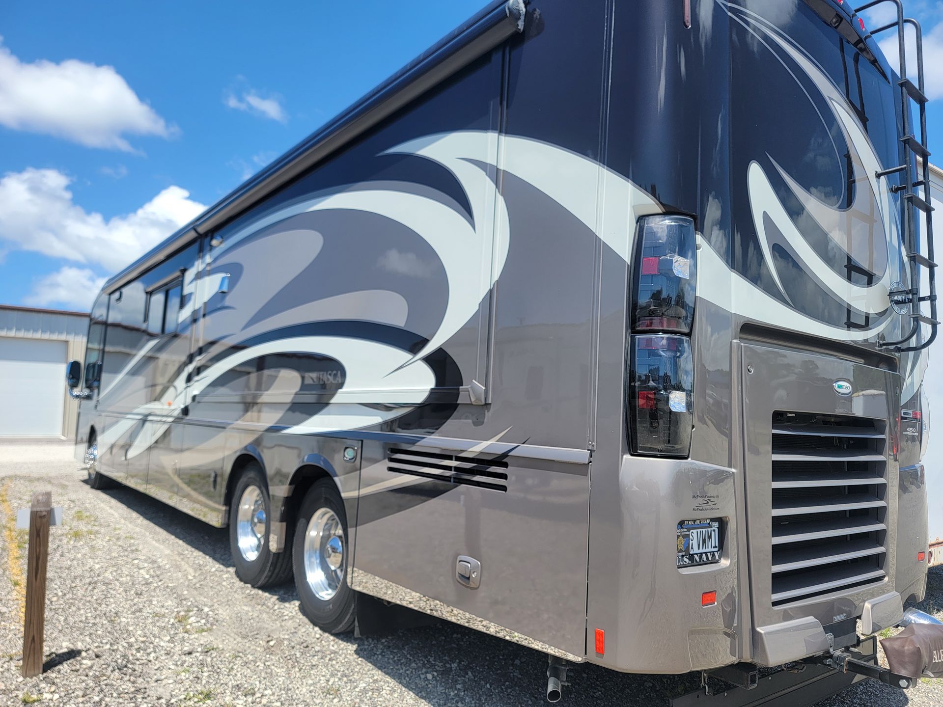 A large rv is parked in a gravel lot.