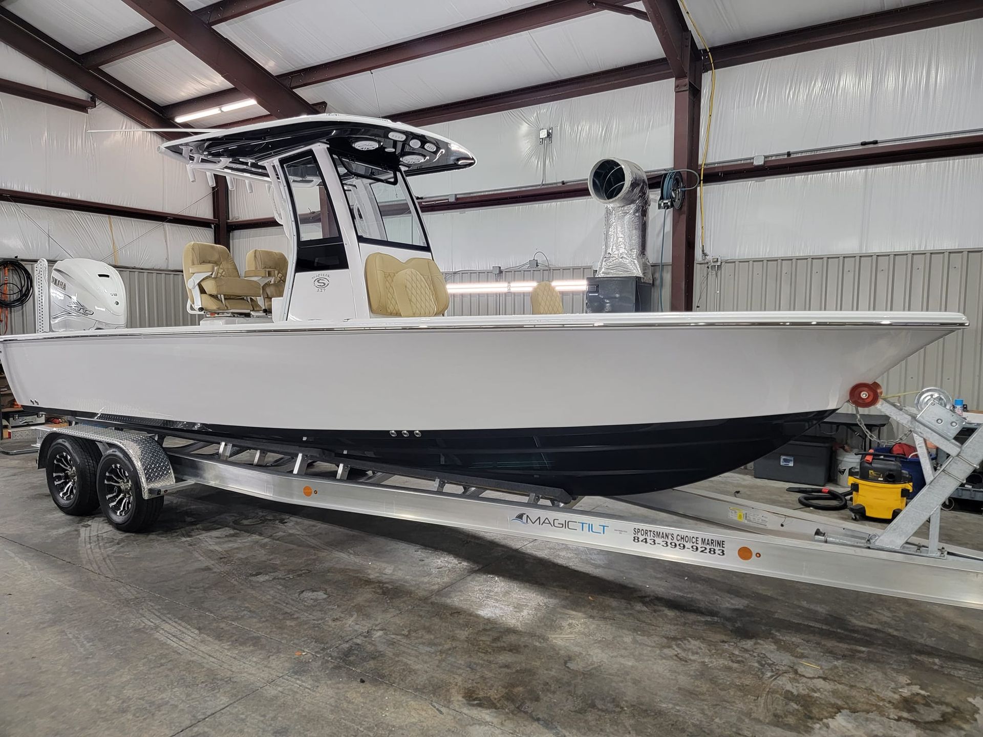 A white boat is parked on a trailer in a garage.