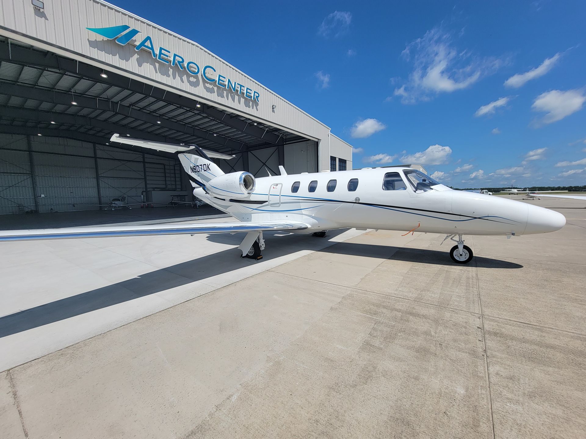 A small white airplane is parked in front of a hangar.