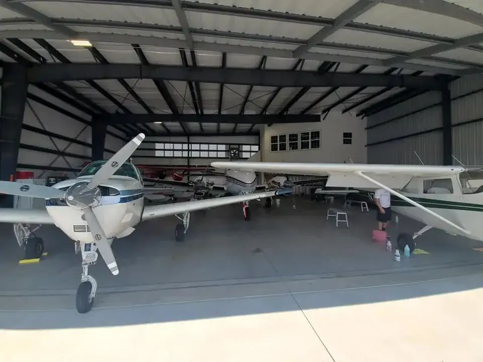 Several small planes are parked inside of a hangar