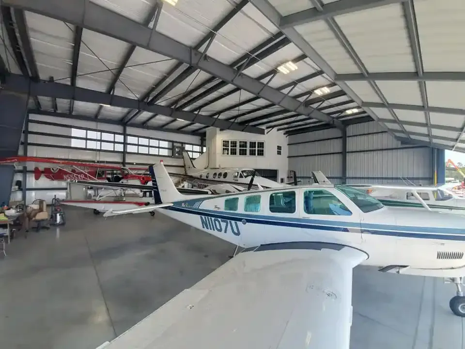 A small plane is parked in a hangar with other planes.