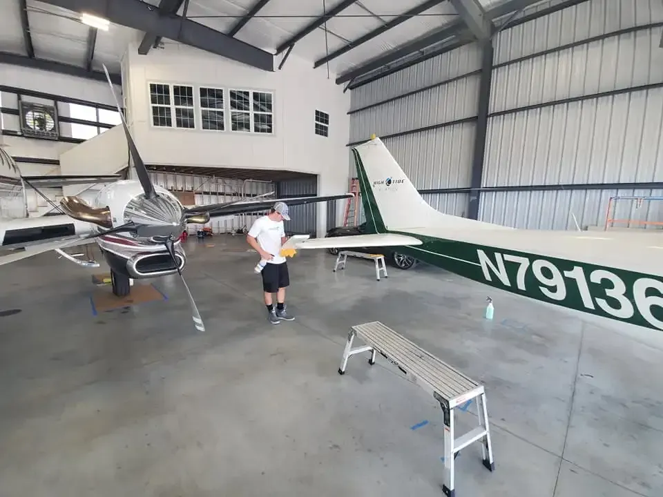 A man is standing in front of a plane in a hangar.