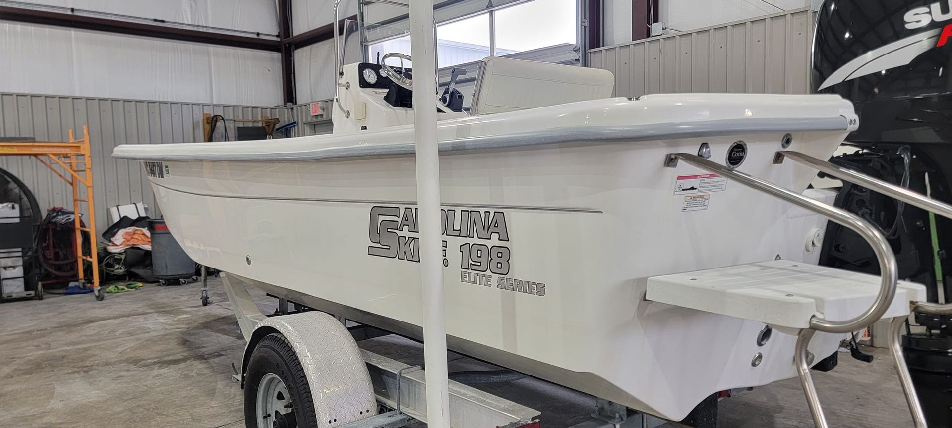 A white boat is sitting on a trailer in a garage.