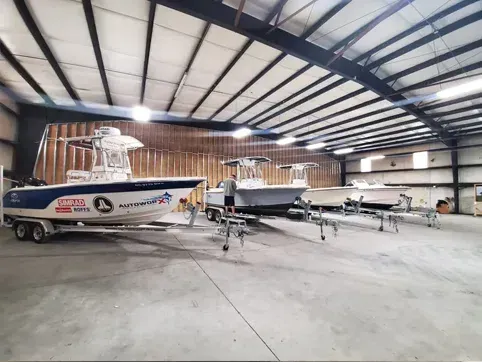 A large warehouse filled with boats and trailers.