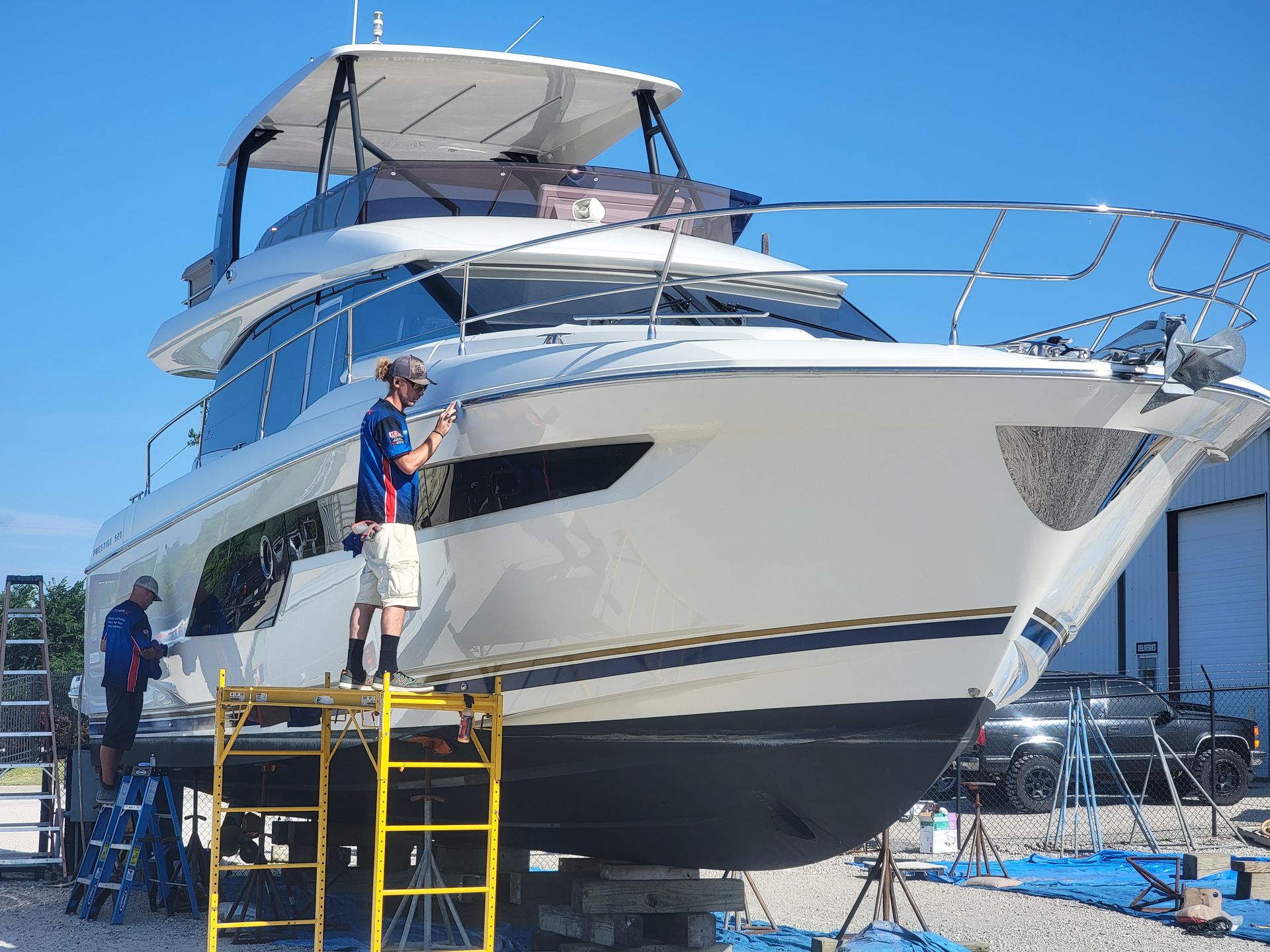 A man is standing on a ladder painting a boat.