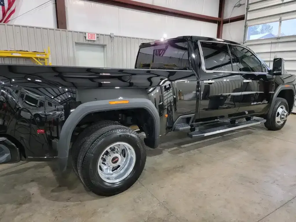 A black truck is parked in a garage next to an american flag.