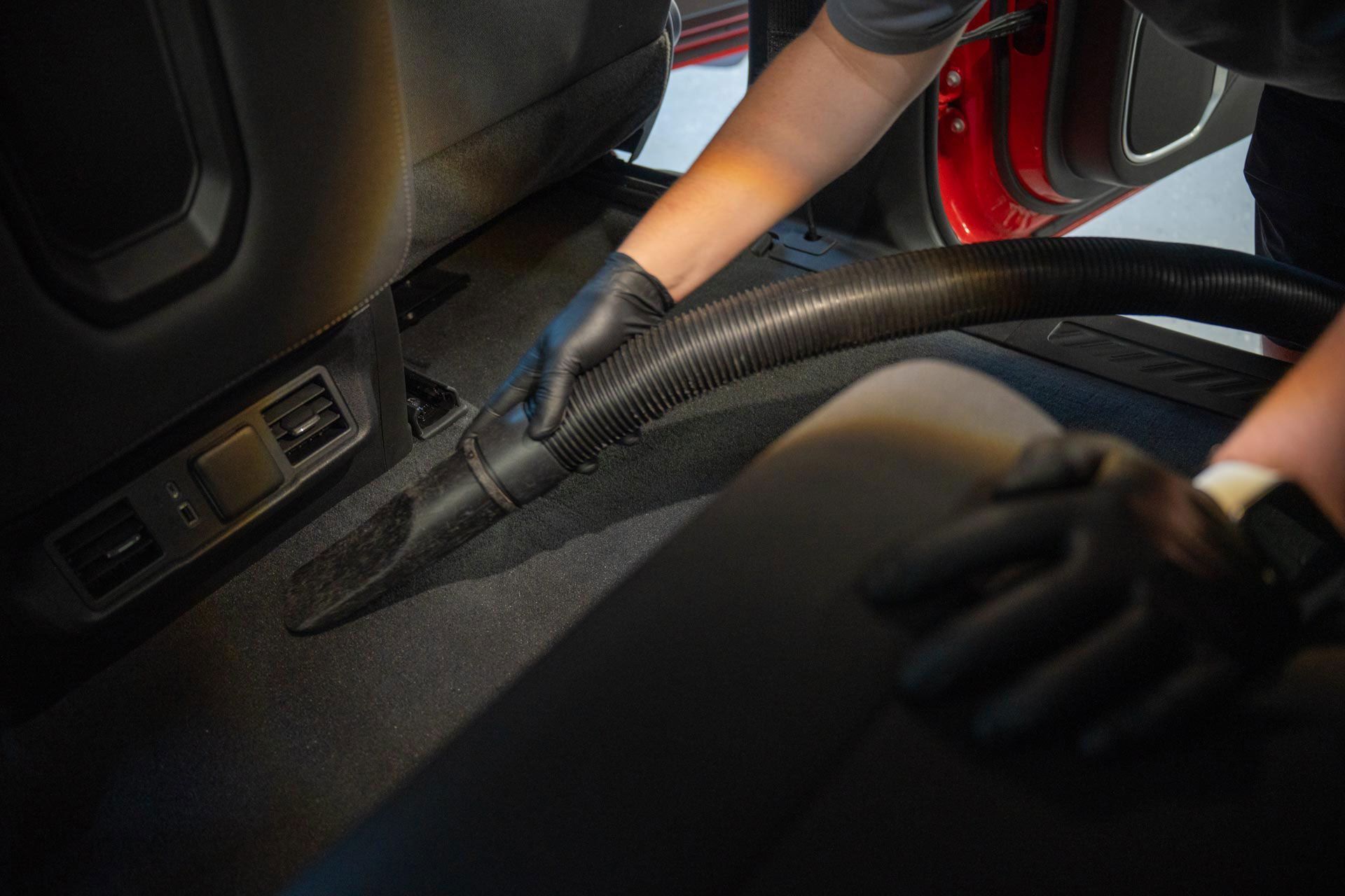 A person is using a vacuum cleaner to clean the floor of a car.