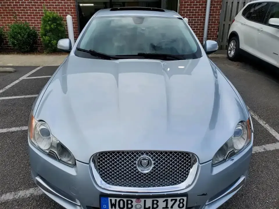 A silver jaguar is parked in a parking lot