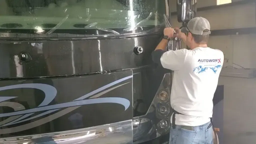 A man wearing a white shirt that says always is working on a bus