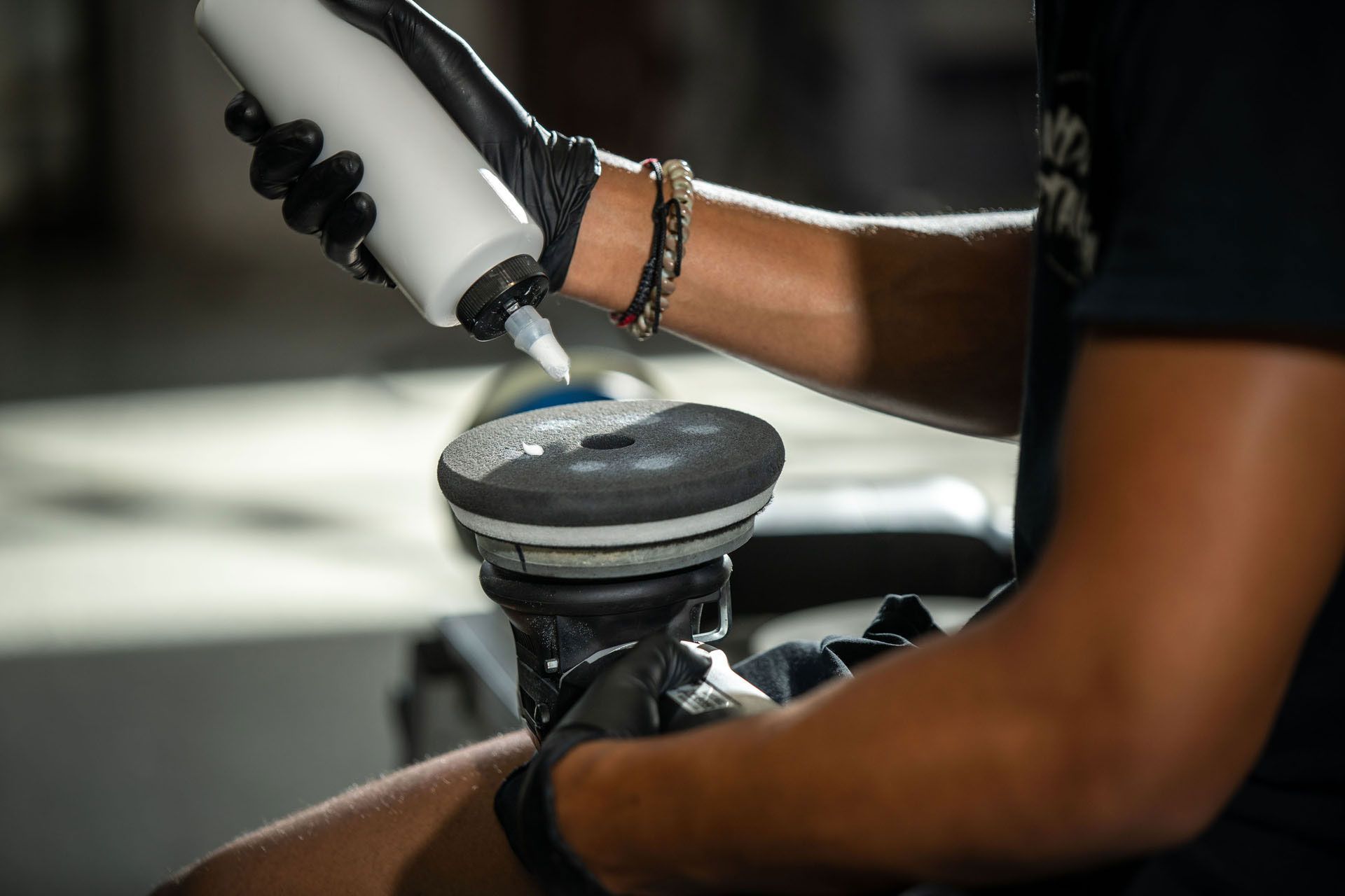 A person is holding a bottle of liquid and polishing a car.