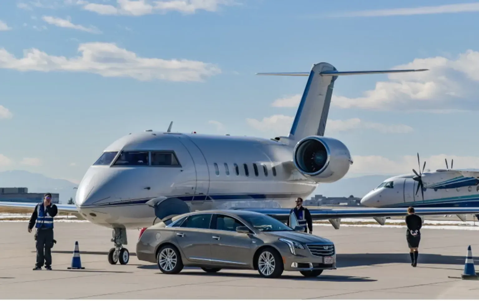 A car is parked in front of a private jet at an airport.