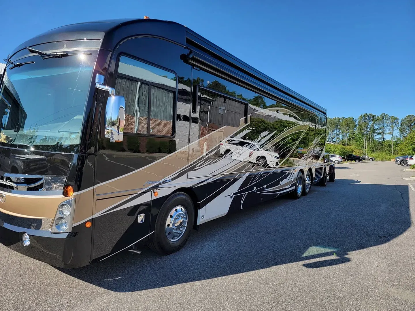 A large black and gold rv is parked in a parking lot.