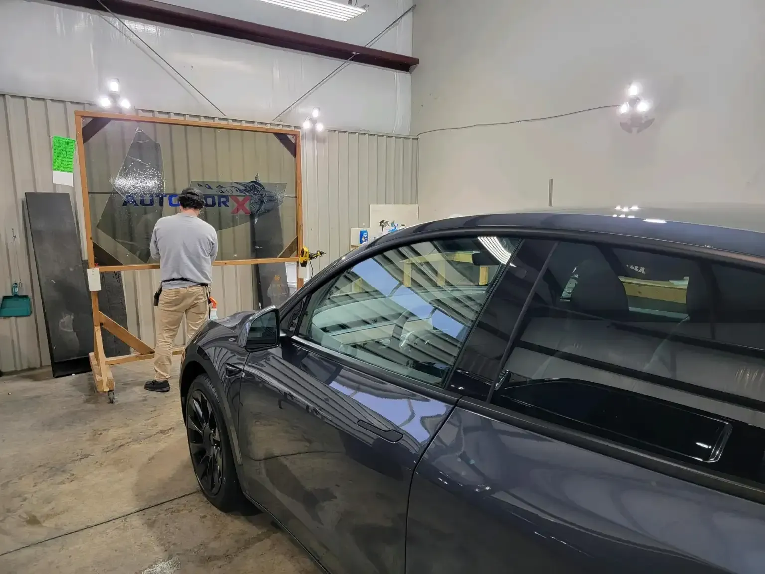 A man is standing next to a car in a garage.