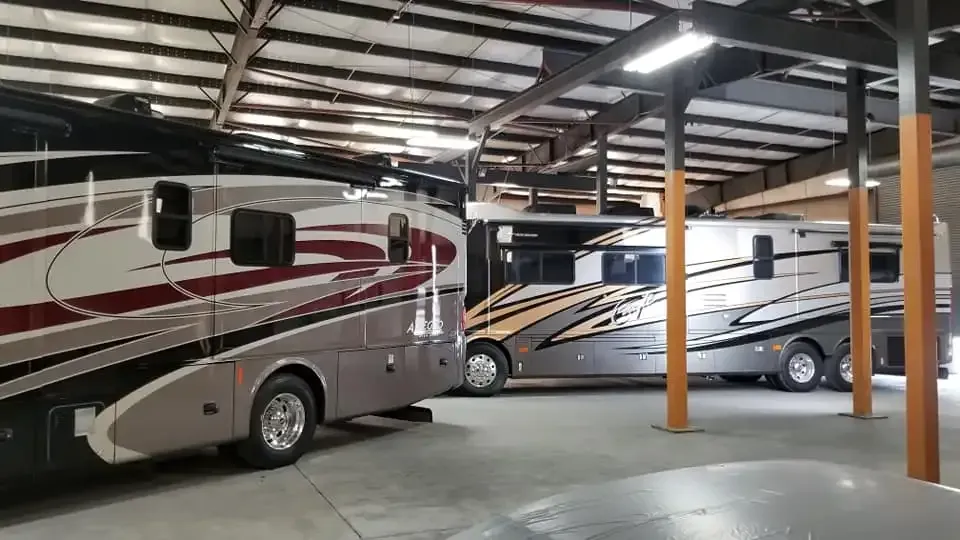 Two rvs are parked in a warehouse.