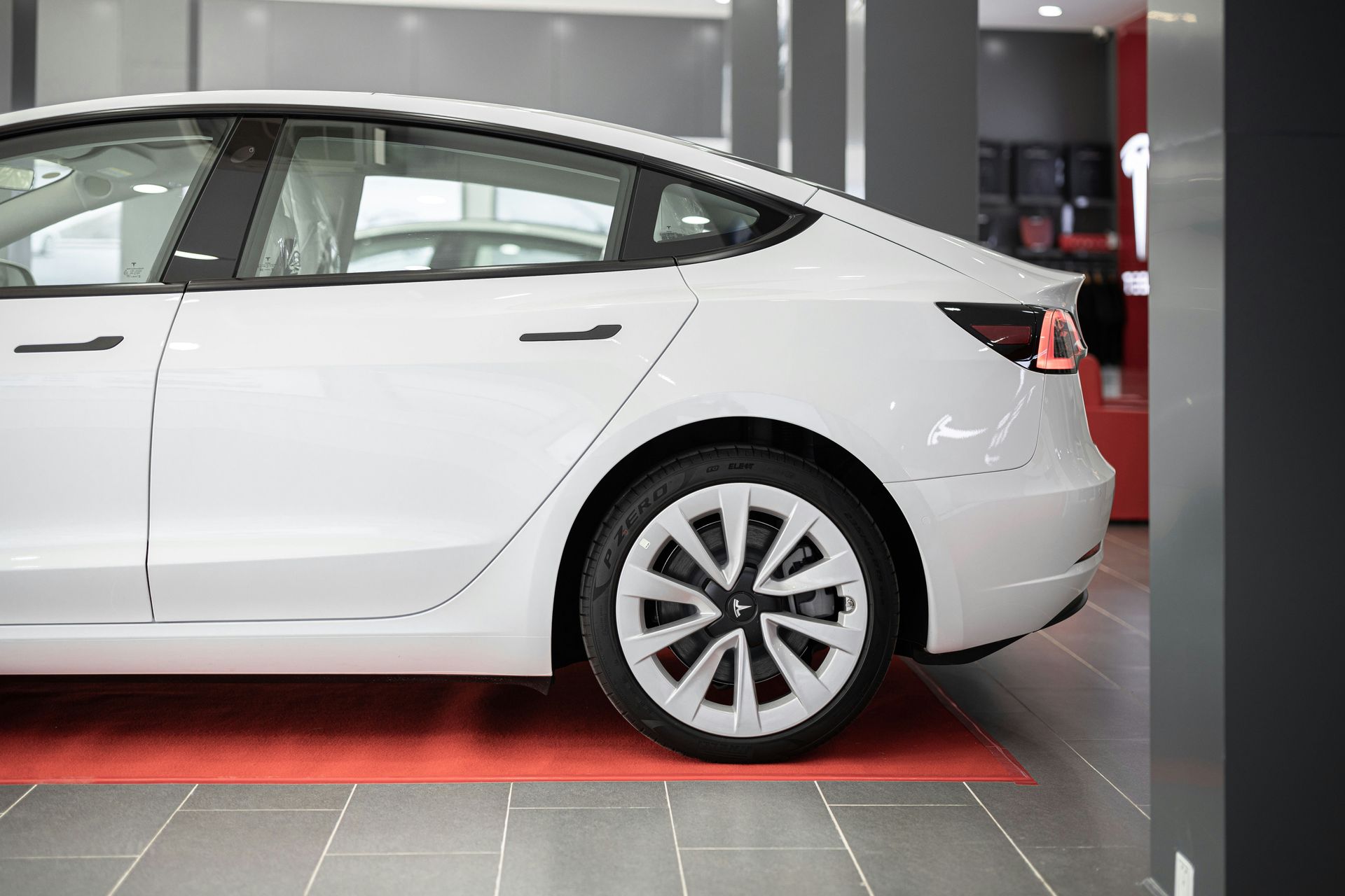 A white tesla model 3 is parked in a showroom.