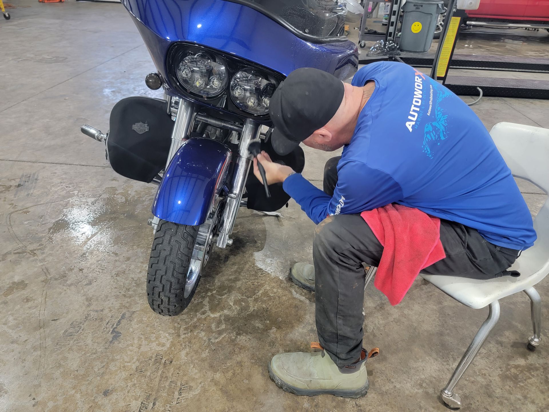 A man in a blue shirt is sitting in front of a blue motorcycle.