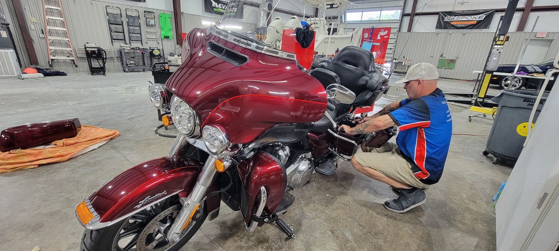 A man is working on a red motorcycle in a garage.