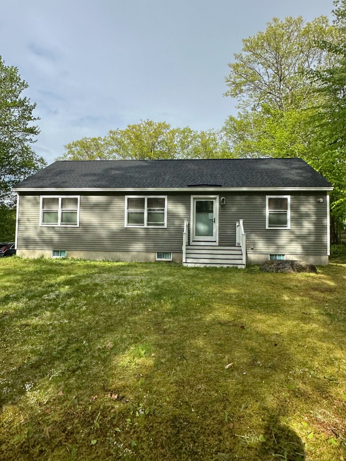 A small house with a black roof is sitting on top of a lush green field.