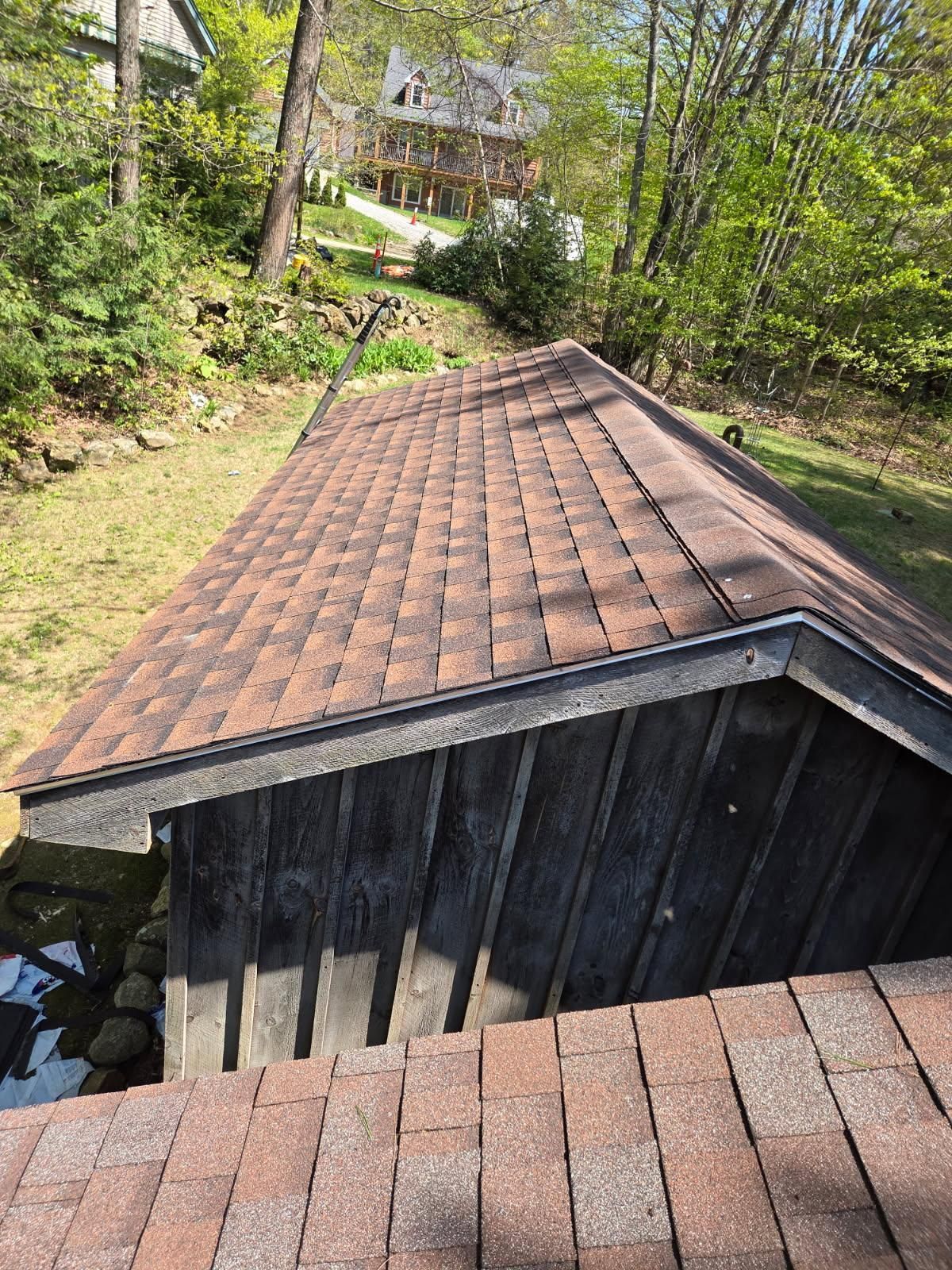 A roof of a building with a house in the background.