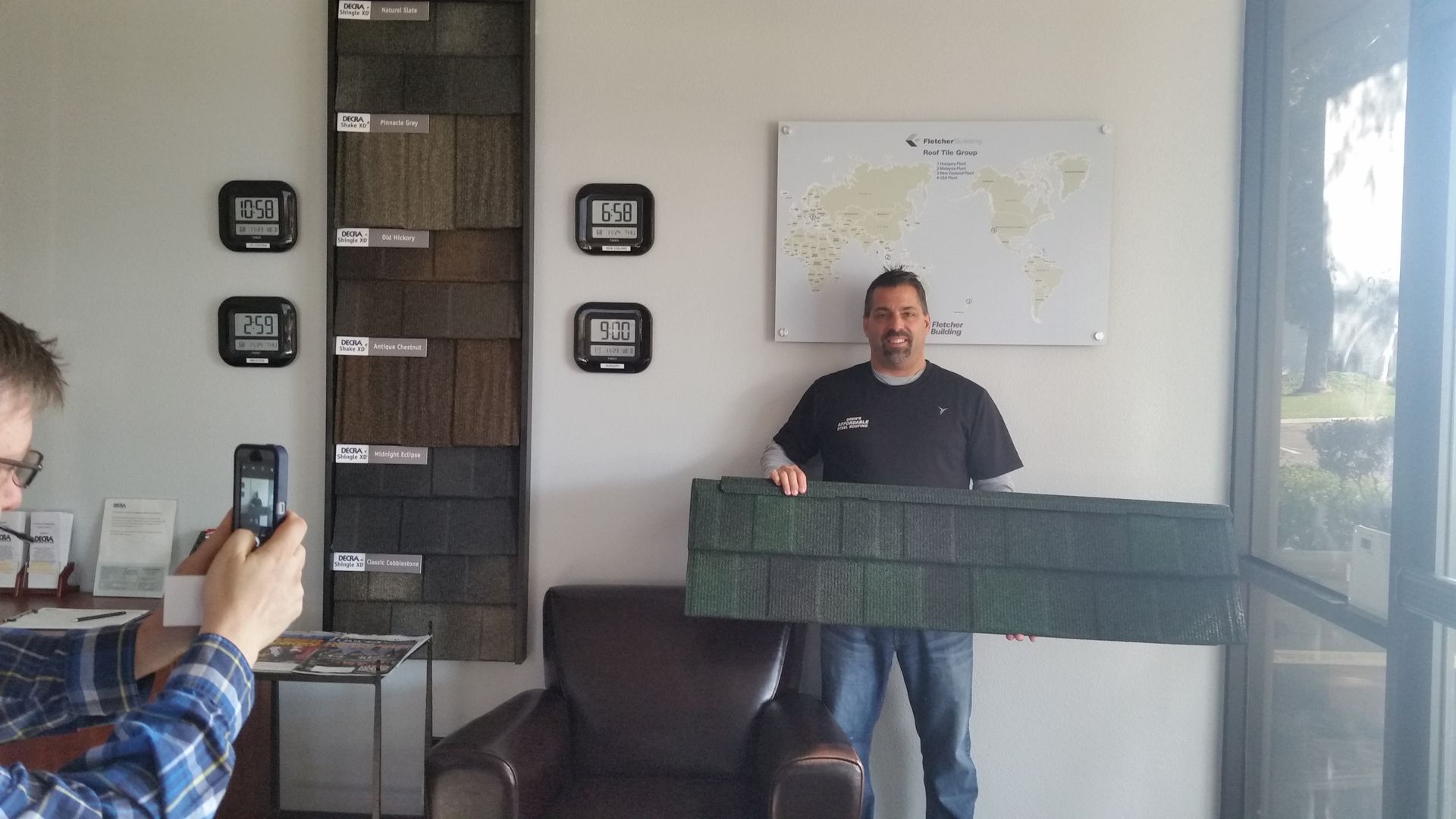 A man is taking a picture of another man holding a piece of wood.