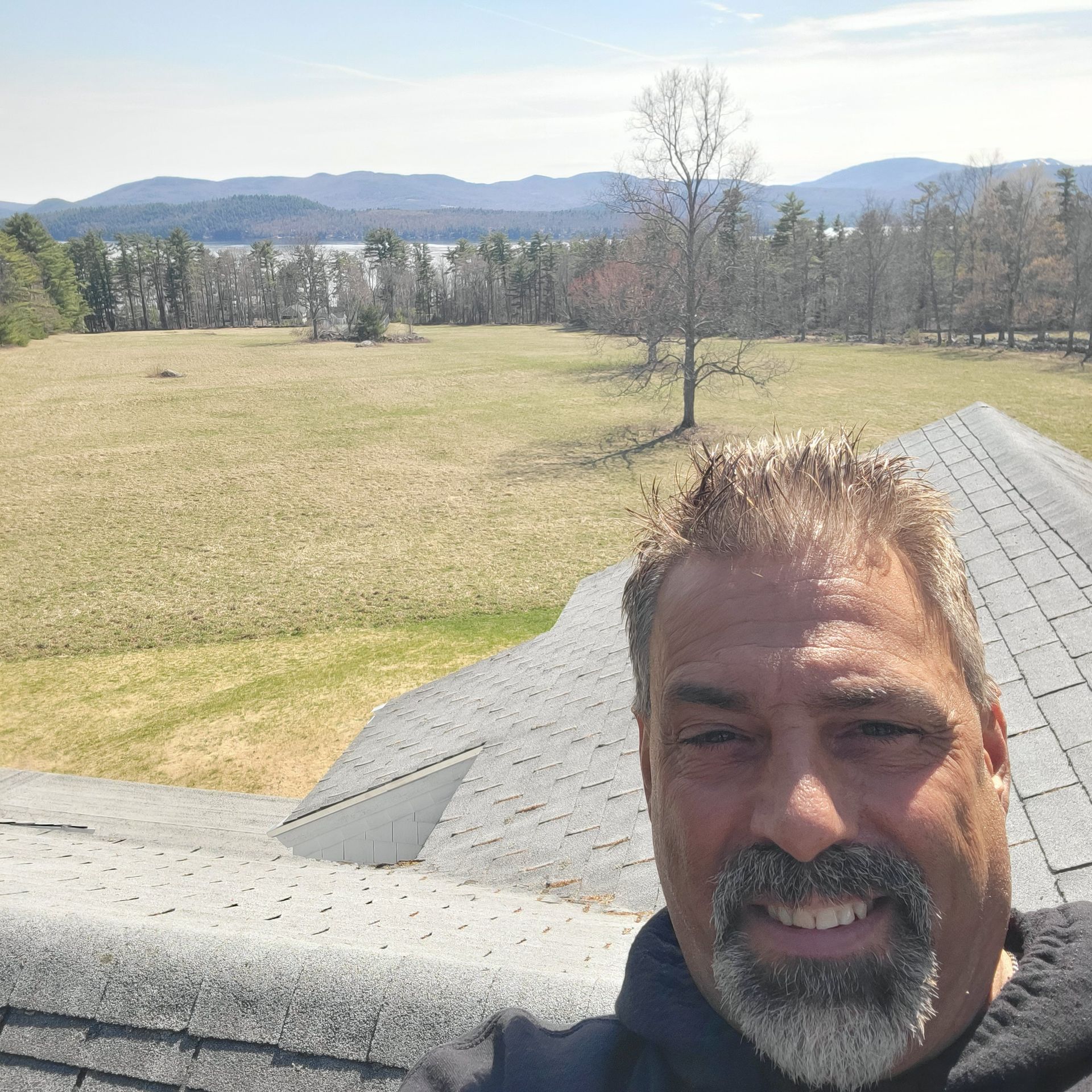 A man with a beard is smiling in front of a field