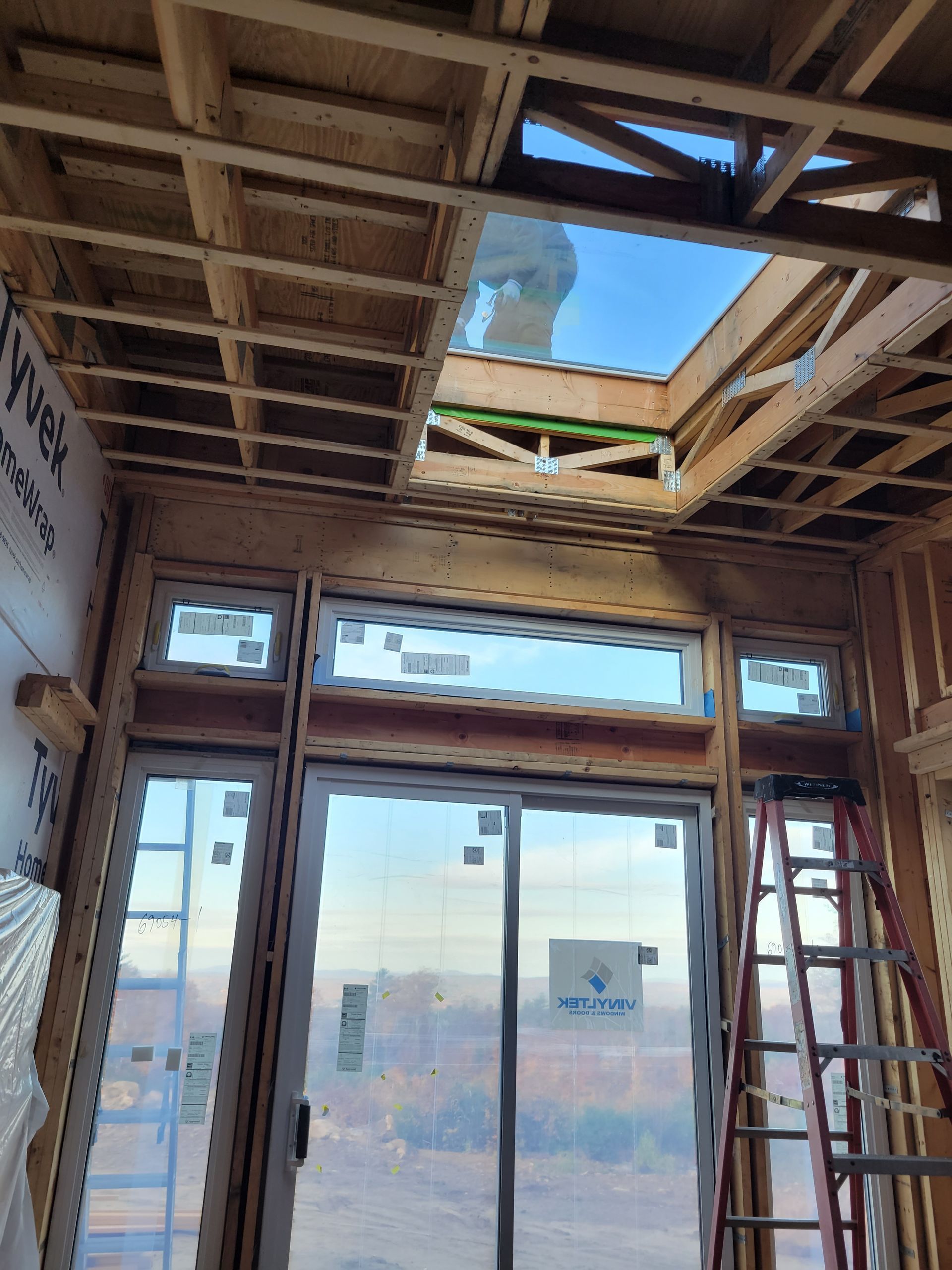 A room under construction with a skylight and a ladder.