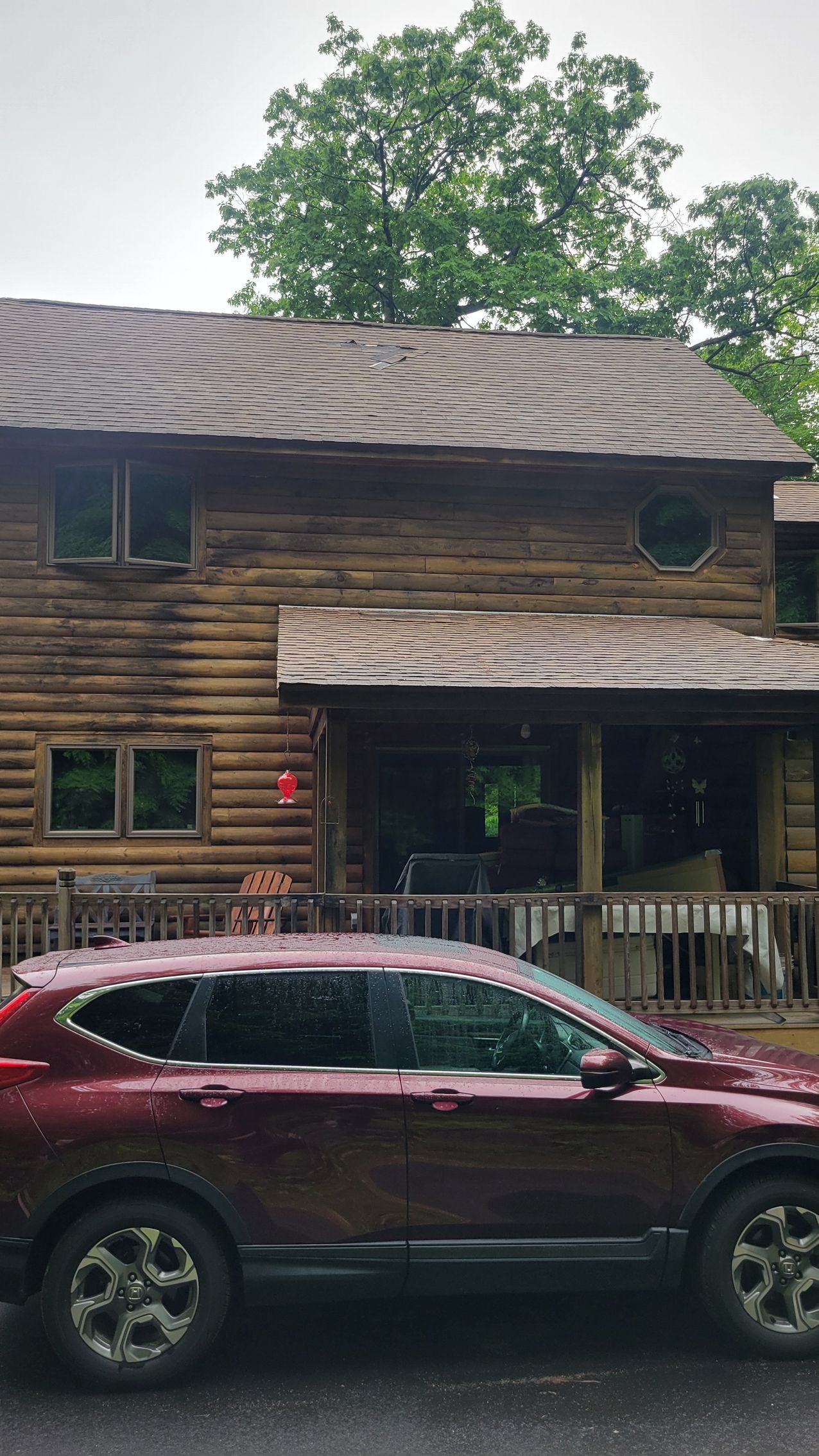 A red car is parked in front of a log cabin.