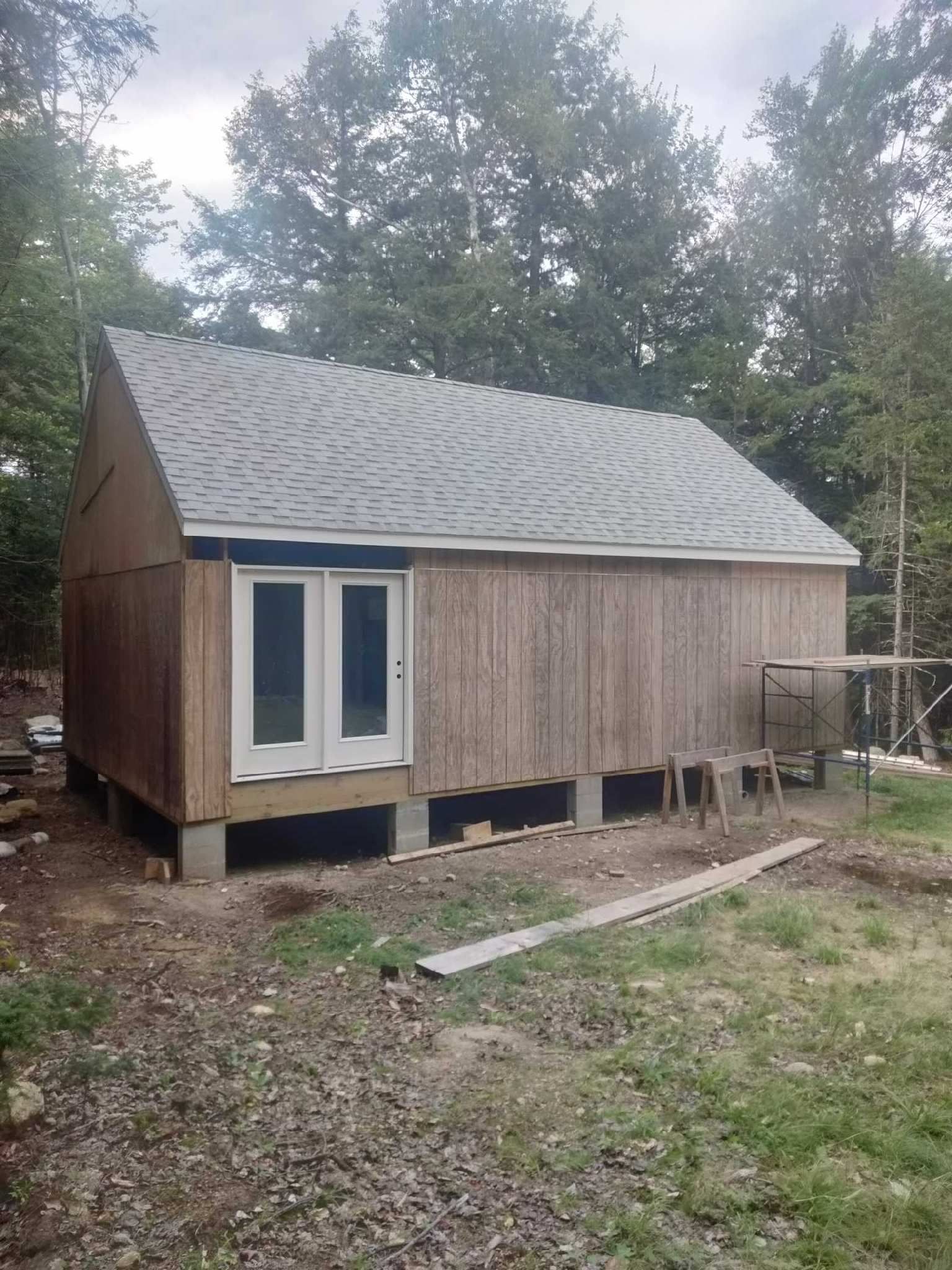 A small house is being built in the middle of a field.