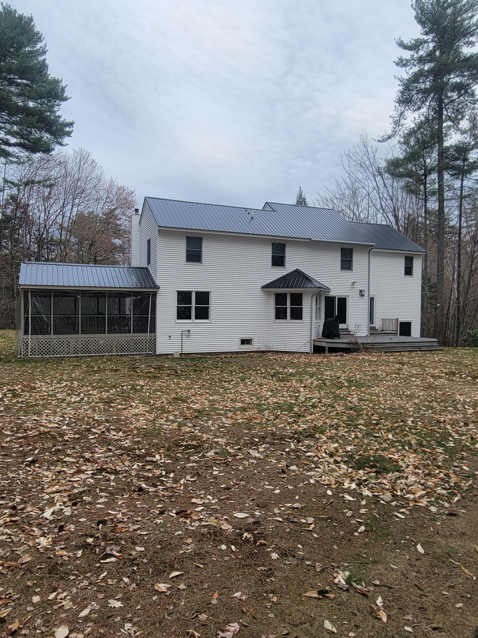 A white house with a metal roof and a screened in porch
