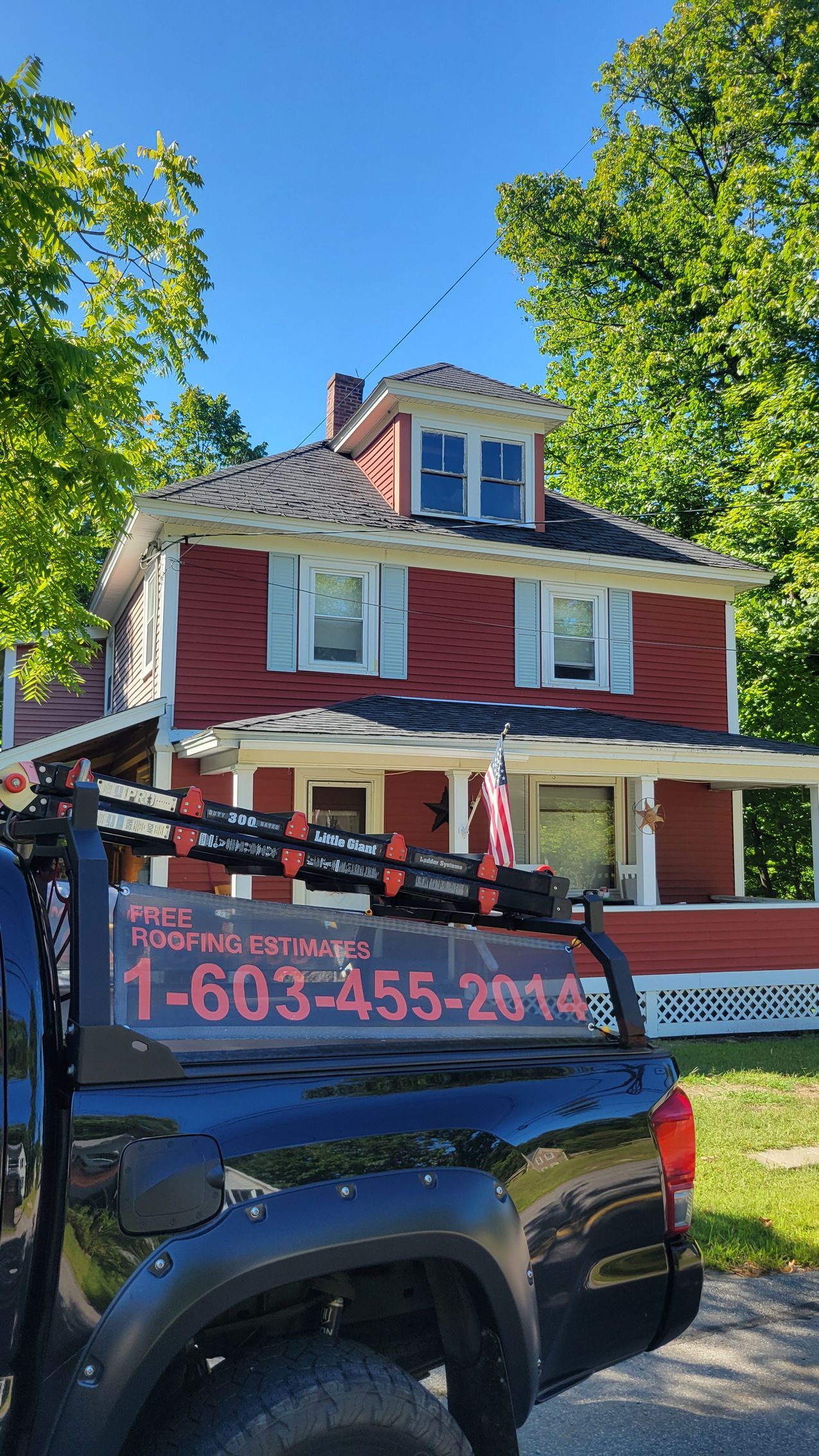 A black truck is parked in front of a red brick house.